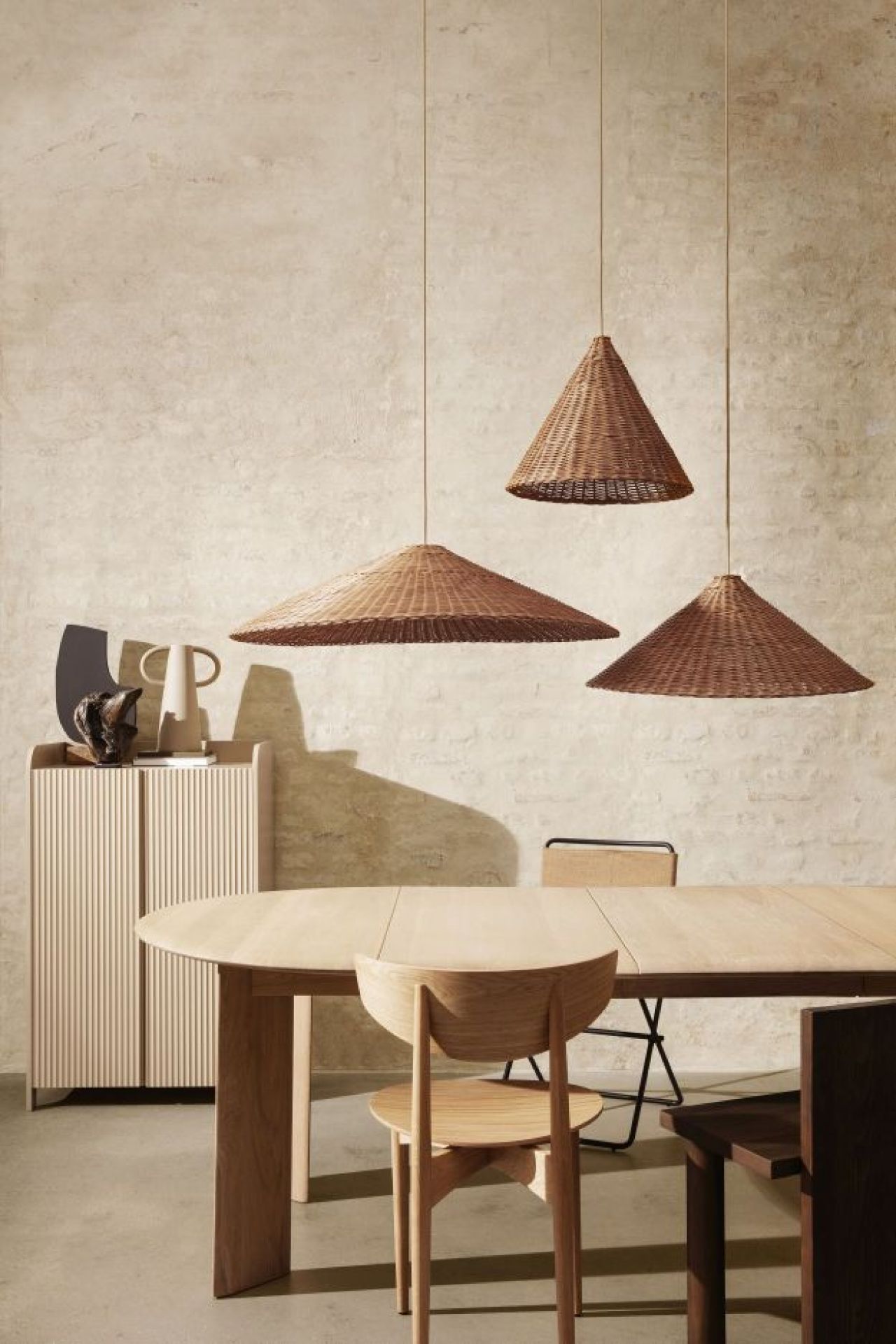 Drei braune Dou Lampenschirme von Ferm Living aus Rattan über einem Esstisch.
