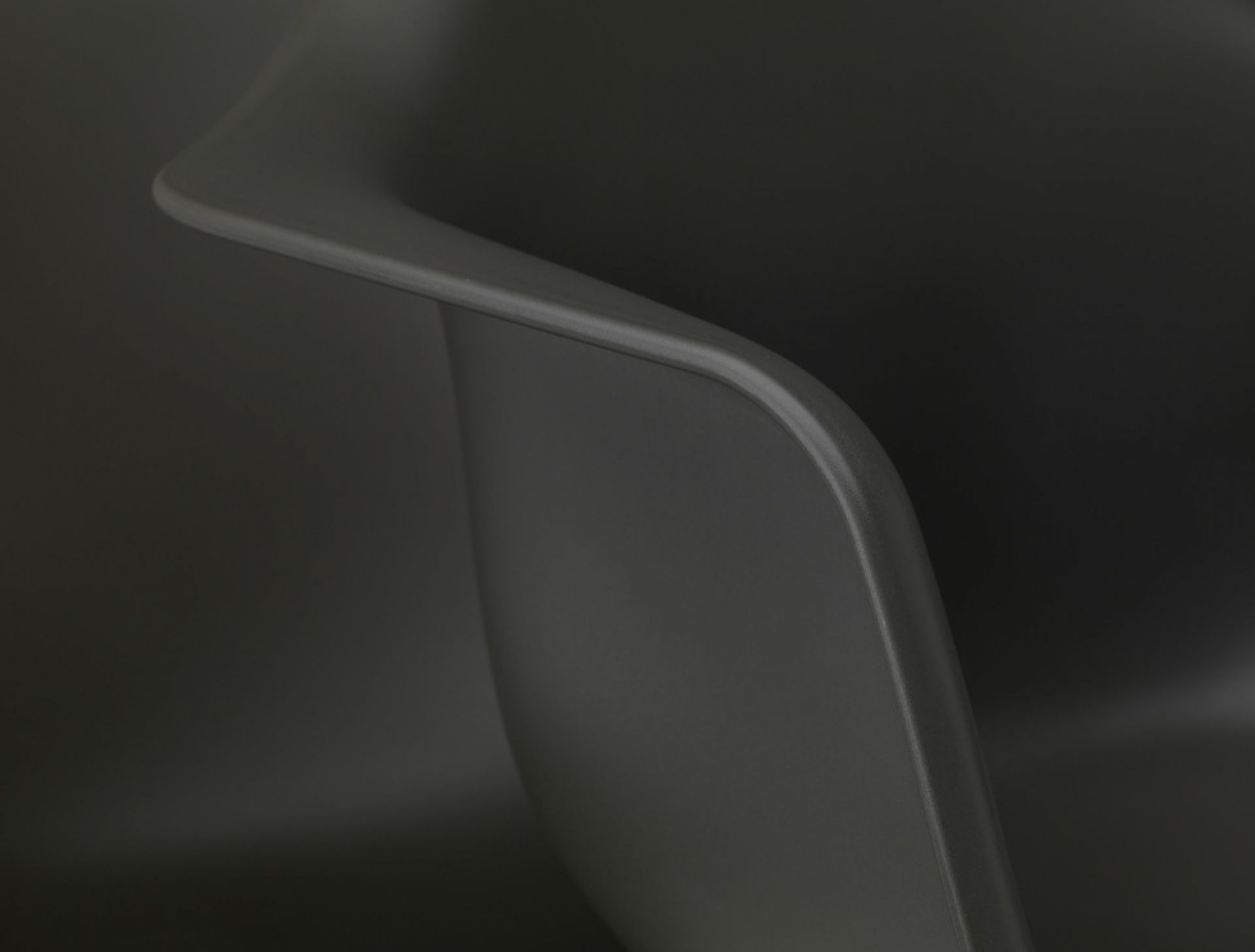 Detailaufnahme der Armlehne eines grauen Eames Plastic Arm Chair PACC Stuhls von Vitra.