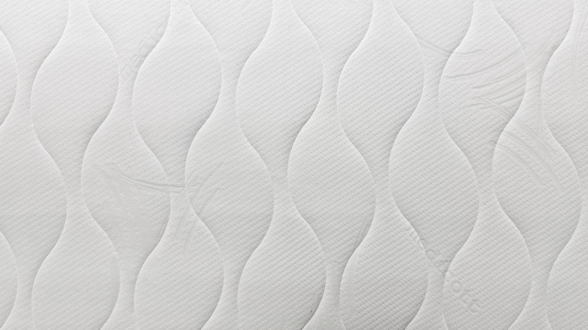 Nahaufnahme der weißen 7-Zonen Hybridschaummatratze mit Wellenmuster für optimalen Schlafkomfort und Druckentlastung.