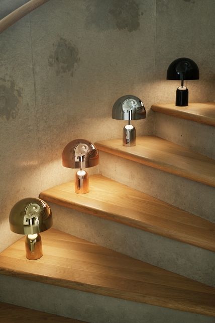 Mehrere Tom Dixon Bell LED Akkuleuchten in verschiedenen Farben auf einer Holztreppe.