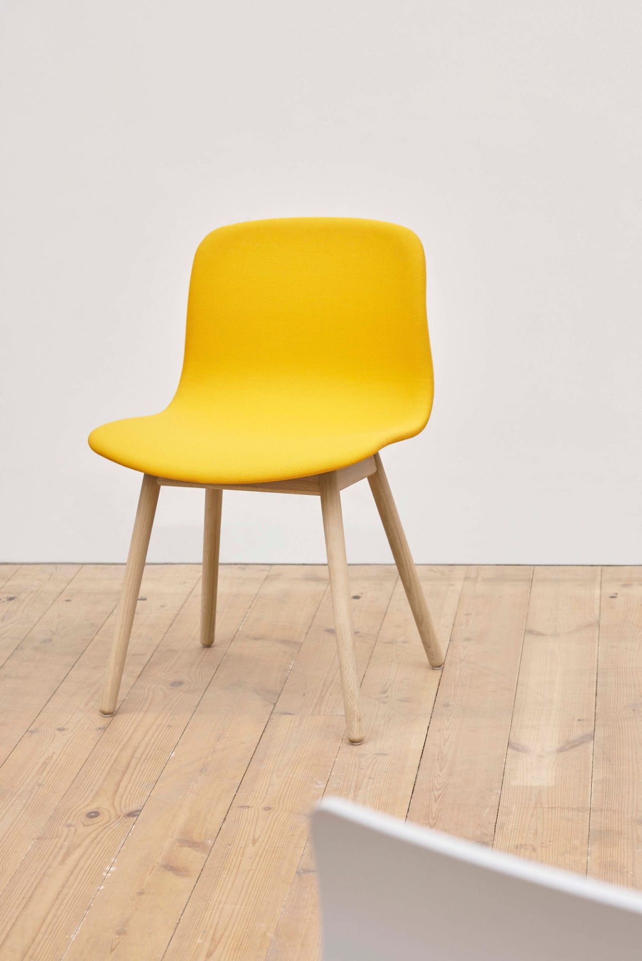 Gelber About A Chair AAC13 Stuhl von Hay mit Vollpolster und Holzbeinen auf Holzboden.