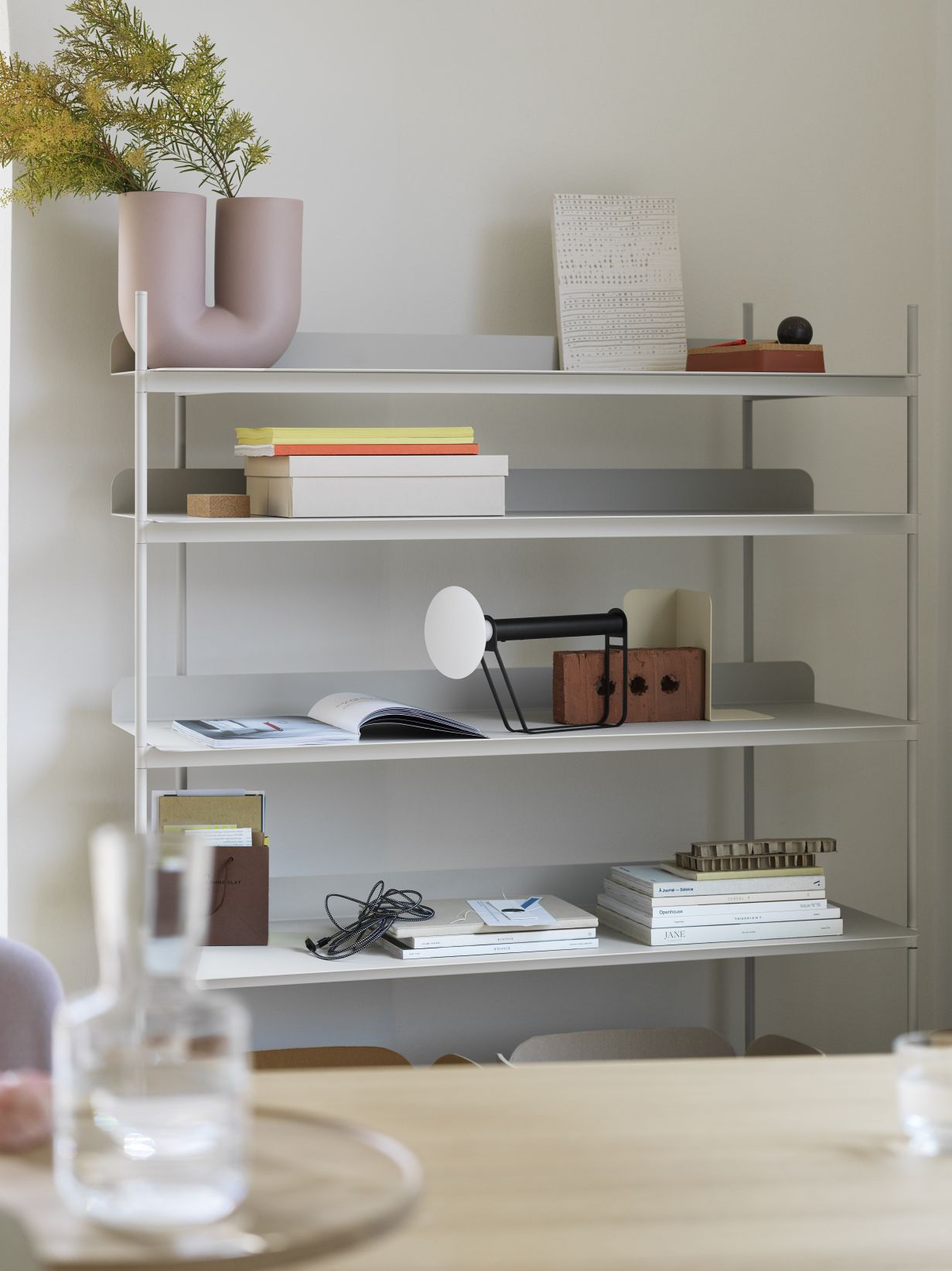 Piton Portable Lamp von Muuto auf einem Regal, moderne Akku Tischleuchte aus Aluminium.