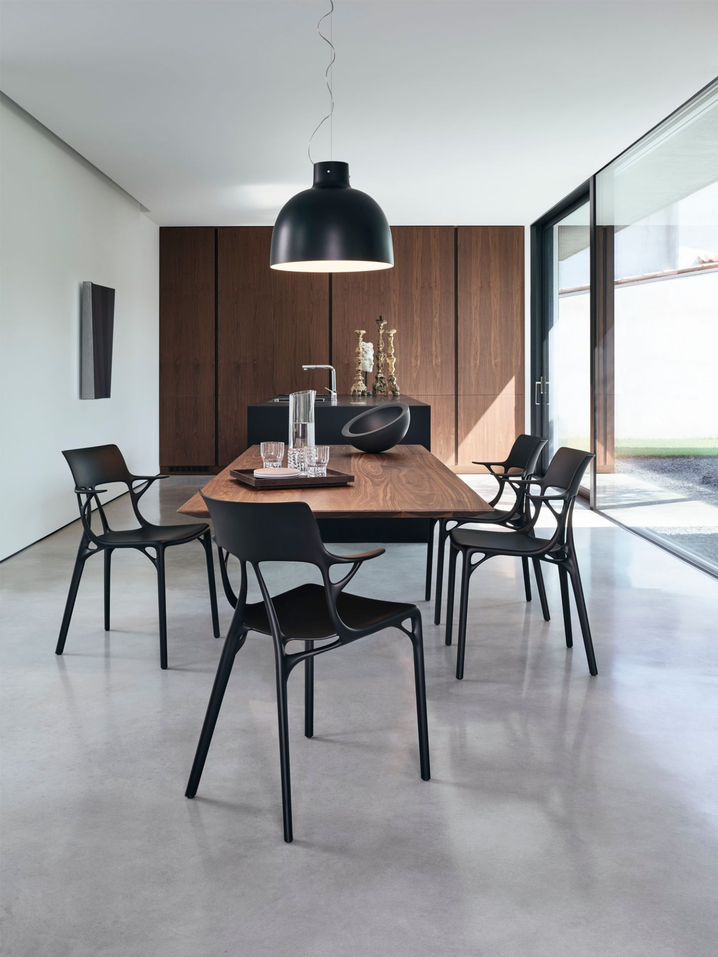 Innenaufnahme: Schwarze Kartell A.I. Stühle um einen Holztisch in modernem Esszimmer. Designermöbel.