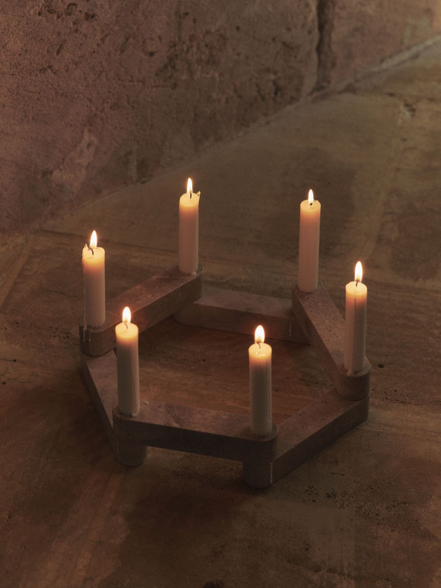 Newel Modular Kerzenhalter von Ferm Living mit sechs brennenden Kerzen auf Steinoberfläche.