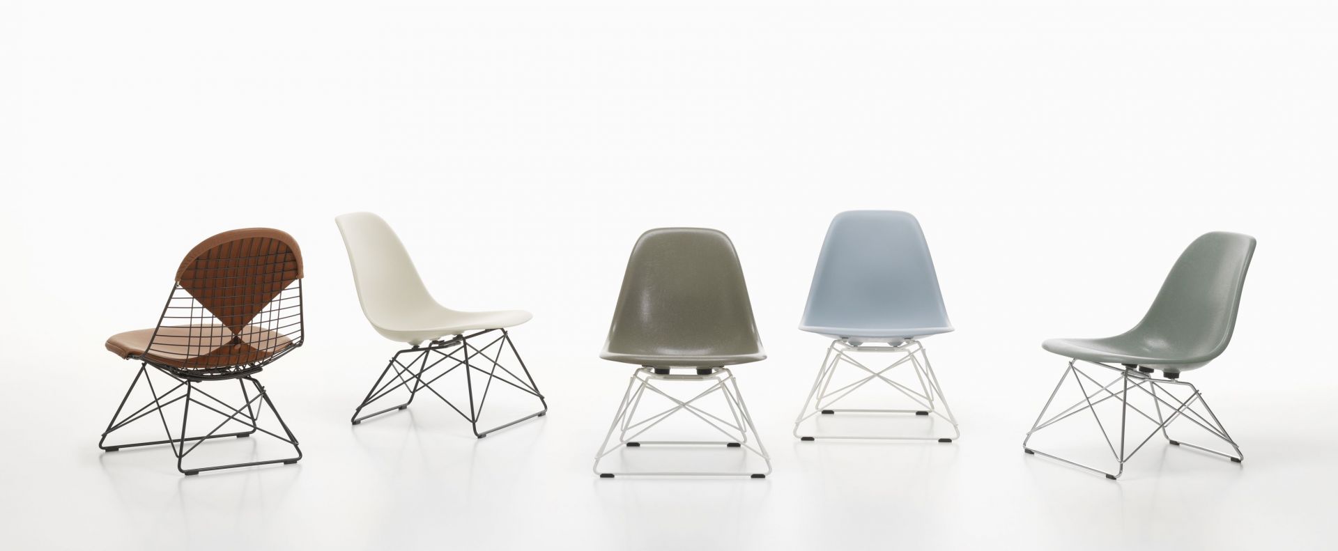 Fünf verschiedene Eames Plastic Side Chairs LSR Stühle von Vitra in einer Reihe auf weißem Hintergrund.