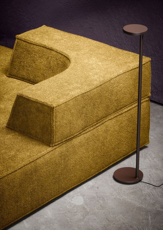 Nahaufnahme des Trio Sofa Eckmoduls in Goldgelb mit Stehlampe im modernen Wohnzimmer.