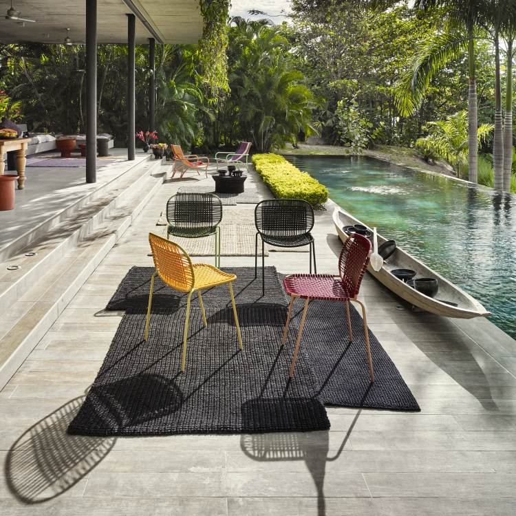 Mehrere Cielo Stacking Chairs in Olive, Gelb und Rot vor Pool. Stapelbarer Outdoor Stuhl.