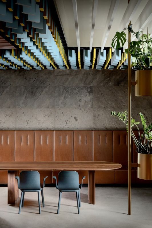 Aeon Comfort Chair Armlehnstuhl Zeitraum vor Holztisch und Lederwand, minimalistisches Design für Esszimmer und Büro.