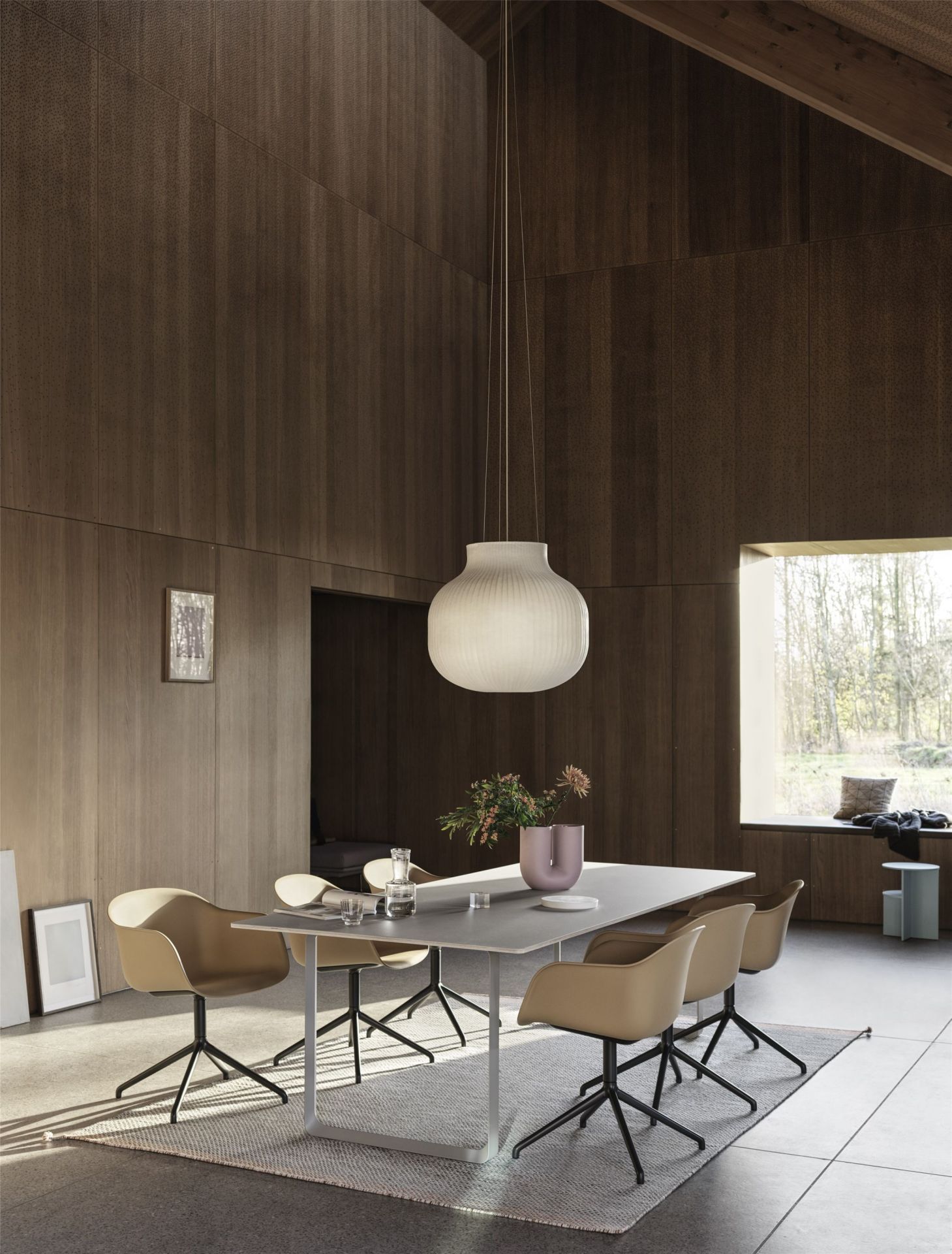 Esszimmer mit Muuto Fiber Armchair Stühlen, Drehfuss, grauem Tisch und moderner Lampe.