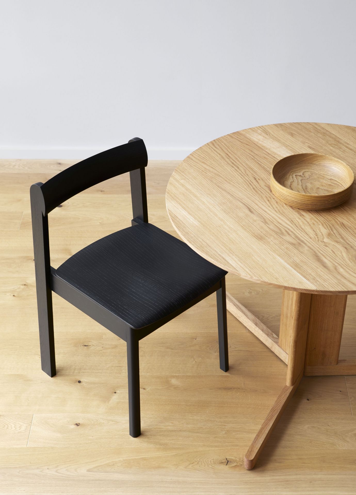 Trefoil Tisch Ø 75 von Form & Refine aus Eiche mit schwarzem Holzstuhl.