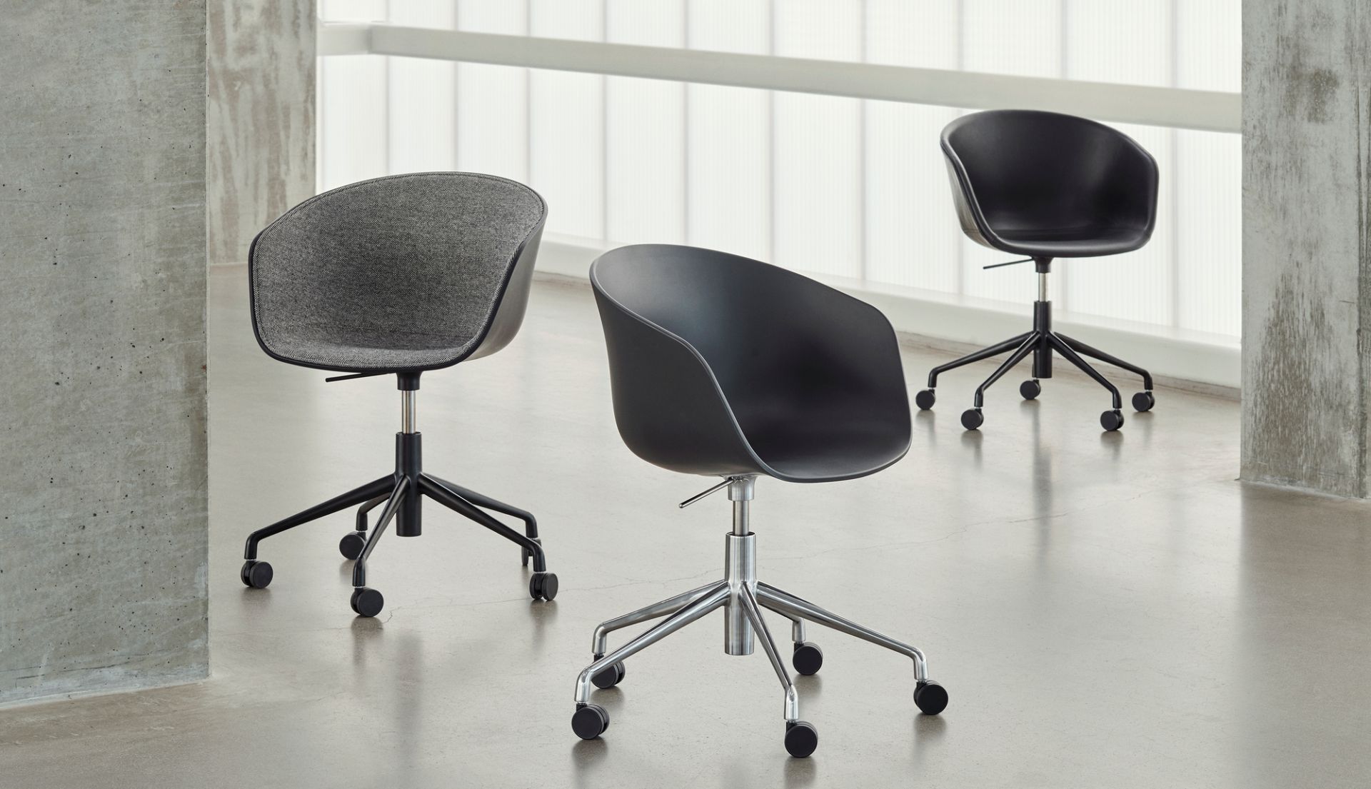 Drei Hay About A Chair AAC25 Bürostühle mit Rollen und Vollpolsterung in Grau und Schwarz.