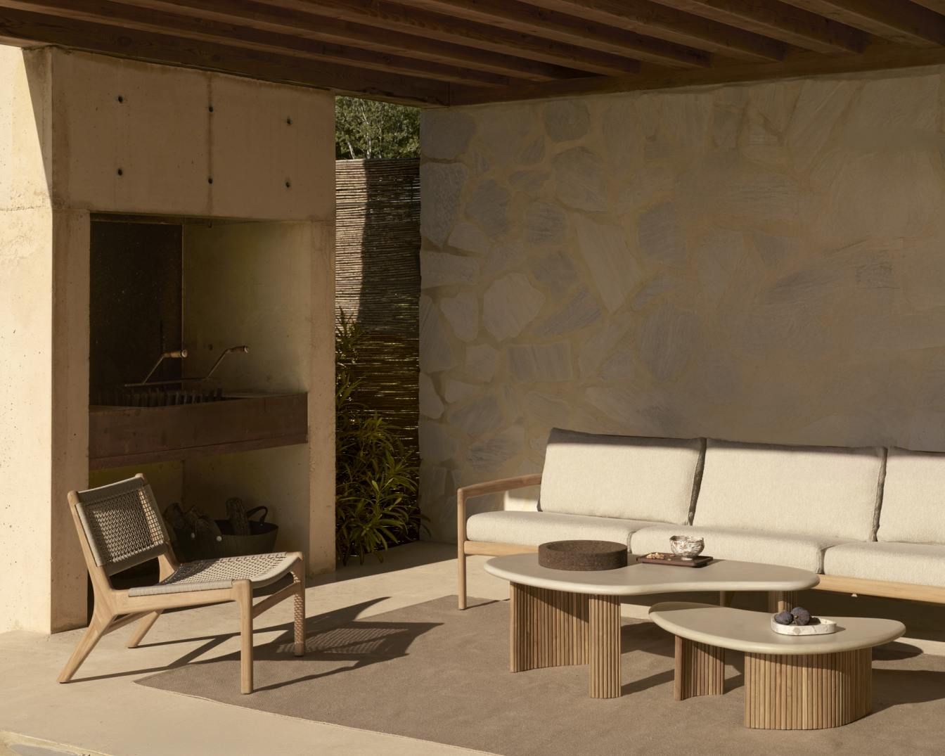 Jack Woven Outdoor Loungesessel aus Teakholz mit beiger Kordel, passendes Sofa und Couchtische auf Terrasse.