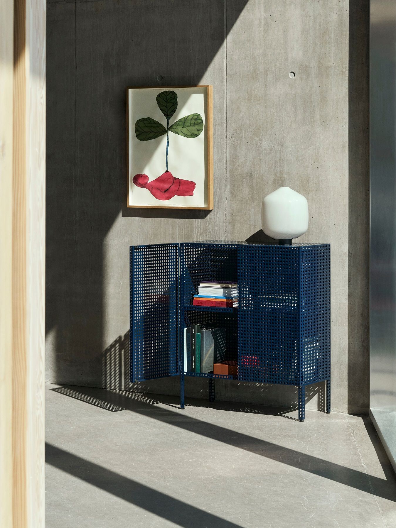 Nahaufnahme der Aspekt Buoy Tischleuchte von Hay auf einem blauen Metallschrank im modernen Interieur.