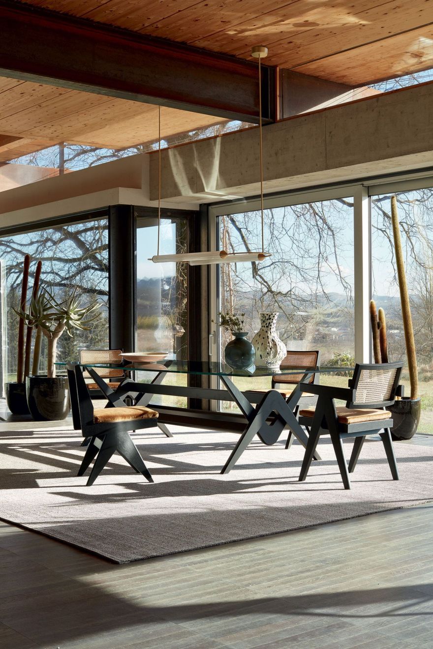 Esstisch: Cassina 056 Capitol Complex Tisch mit Glasplatte und schwarzen Stühlen in modernem Interieur.