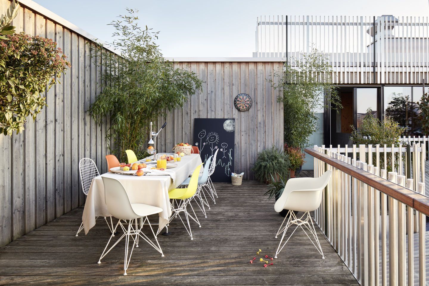 Eames Plastic Arm Chair DAR Stuhl von Vitra auf einer Dachterrasse mit Esstisch.
