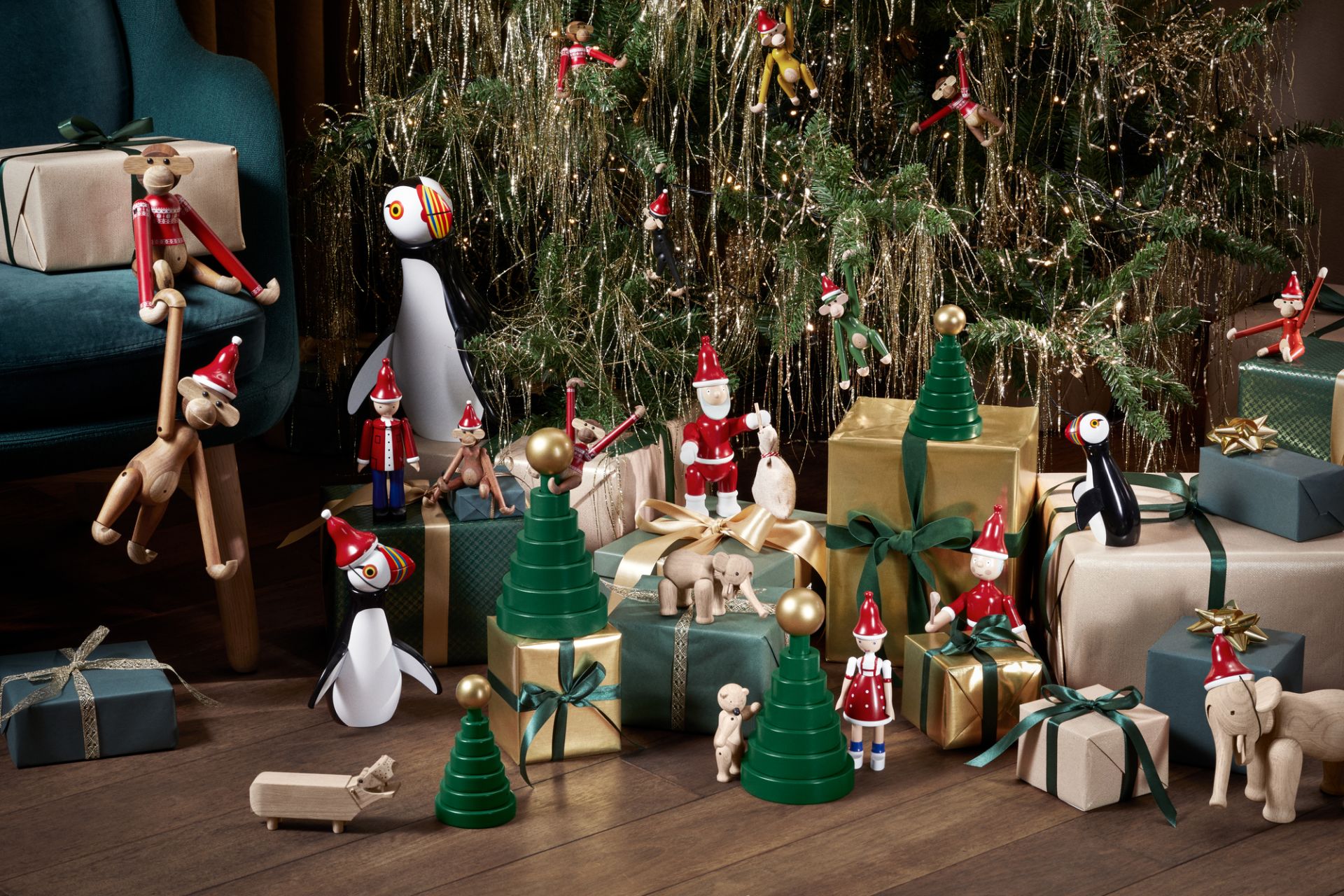 Festliche Szene mit Kay Bojesen Holzfiguren, darunter der Christmas Jumper Affe 2024, unter einem geschmückten Weihnachtsbaum.