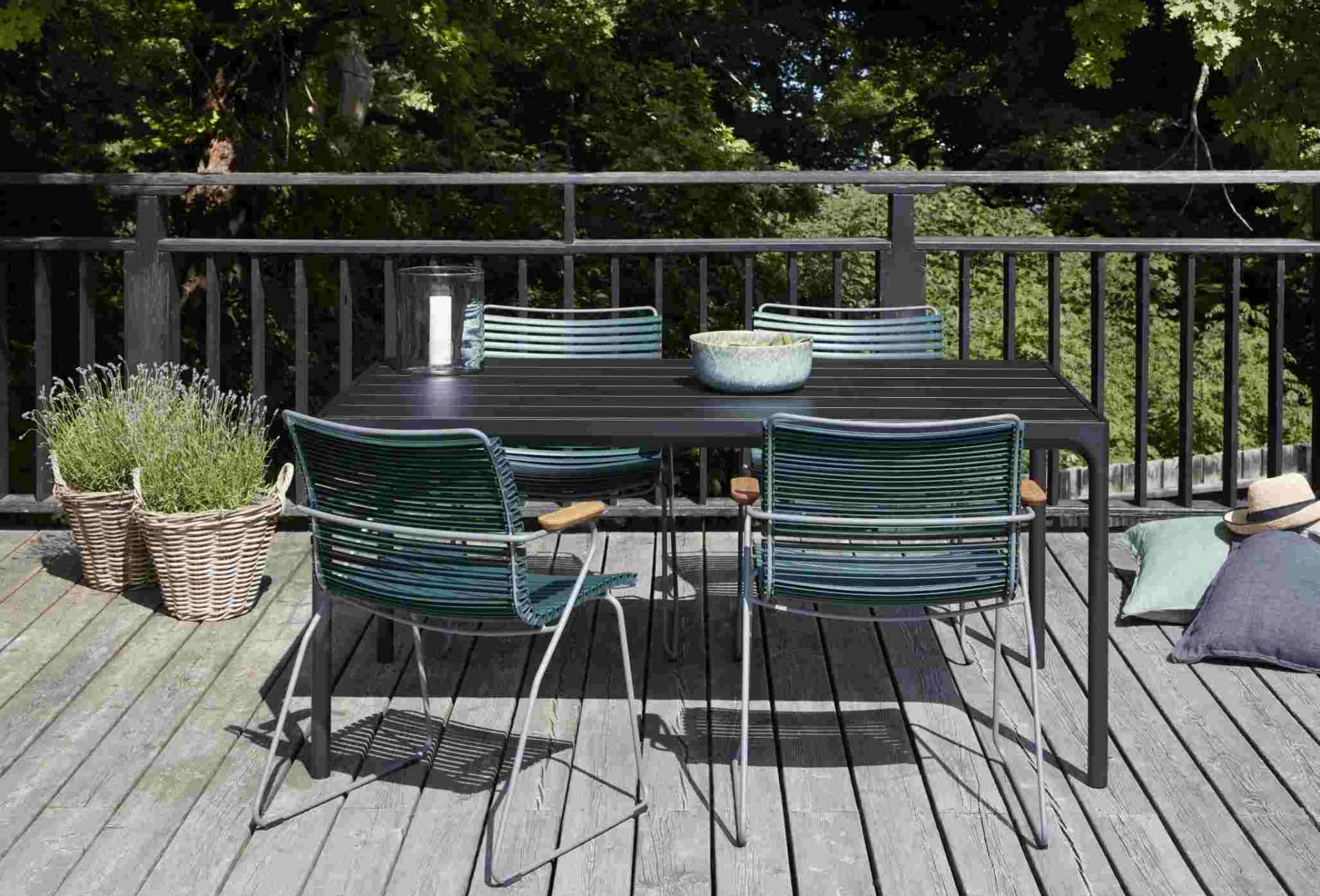 Dunkelgrauer Click Dining Stuhl mit Armlehne von Houe, Teil einer modernen Outdoor-Essgruppe auf Holzterrasse.