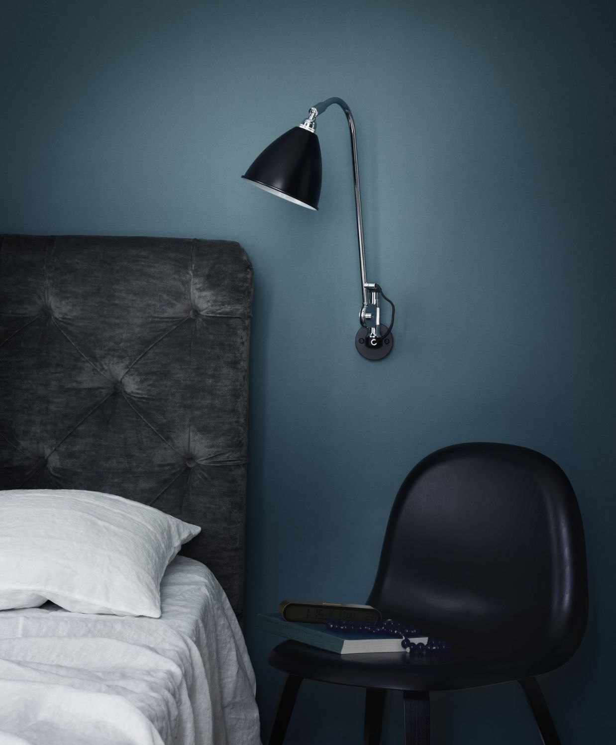 Bestlite BL6 Wandleuchte von Gubi in Schwarz und Chrom über einem Bett.
