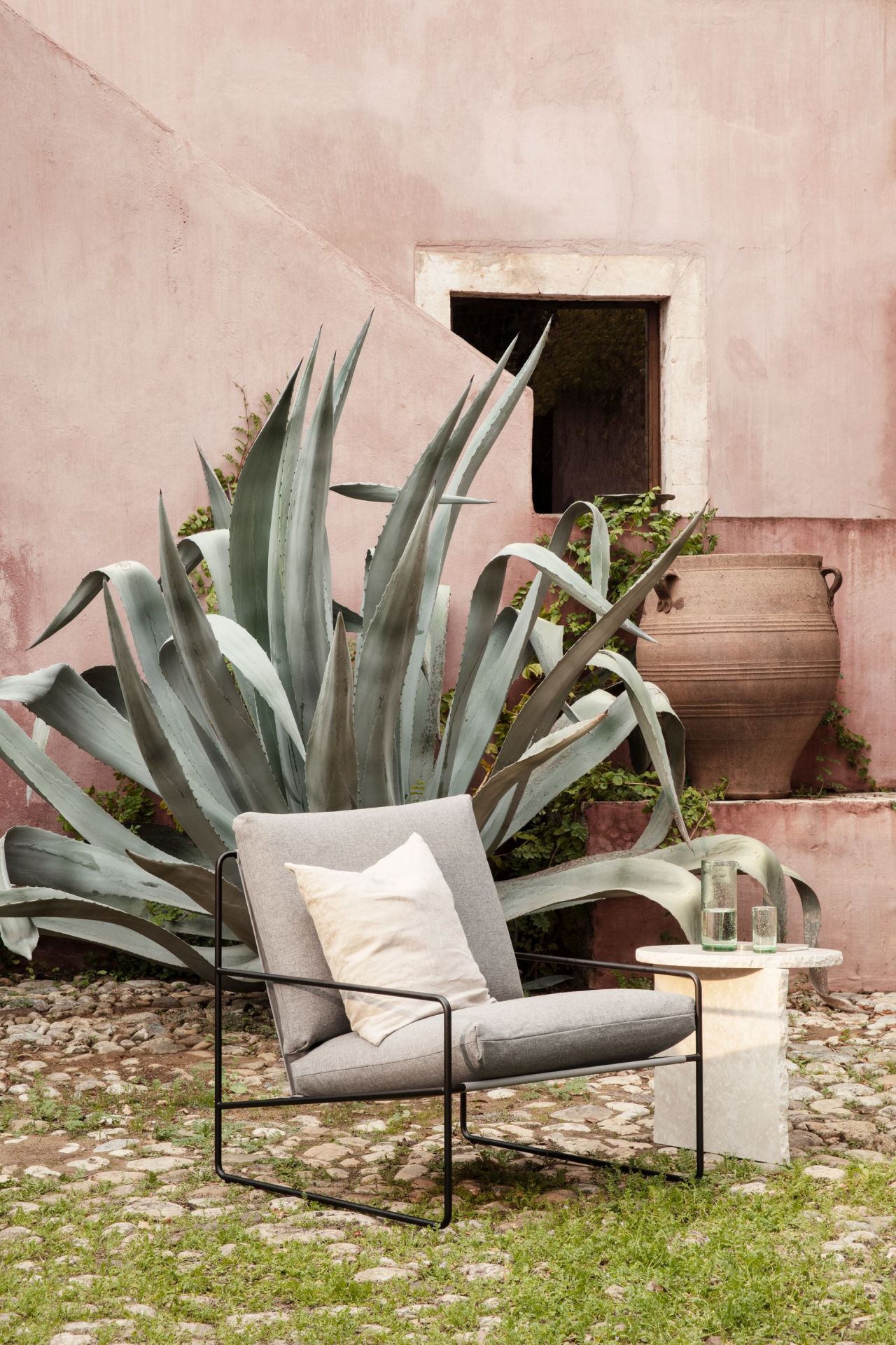 Desert Sessel: Ferm Living Outdoor Sessel mit Cashmere-Bezug und schwarzem Gestell im Garten.