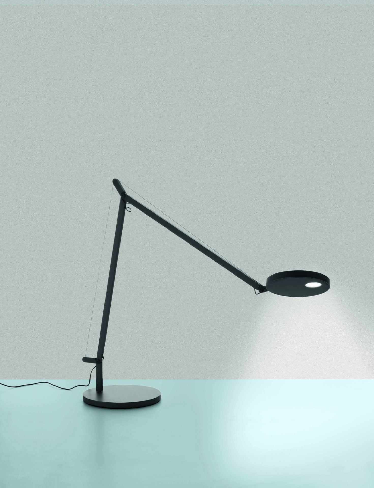 Demetra Tischleuchte von Artemide: Schwarze Schreibtischlampe mit verstellbarem Arm und rundem Leuchtenkopf.