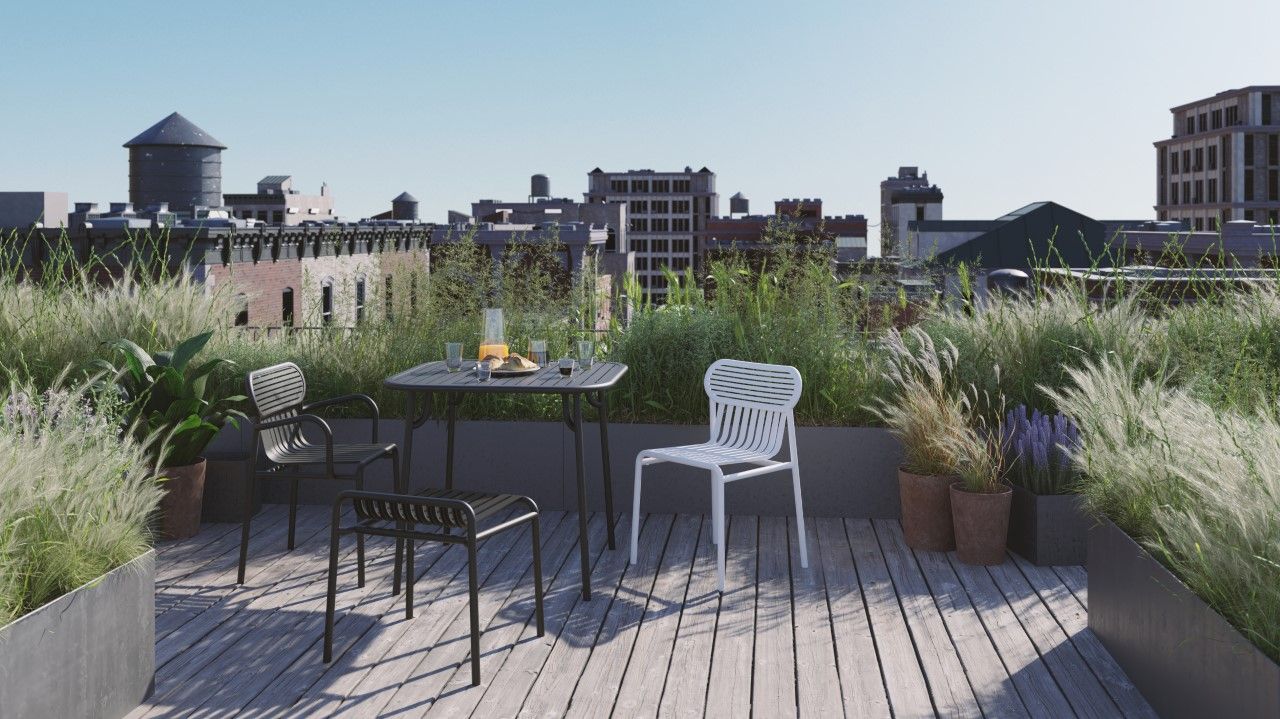 Blauer Petite Friture Week-End Stool Hocker aus Metall auf einer Dachterrasse mit Tisch und Stühlen.