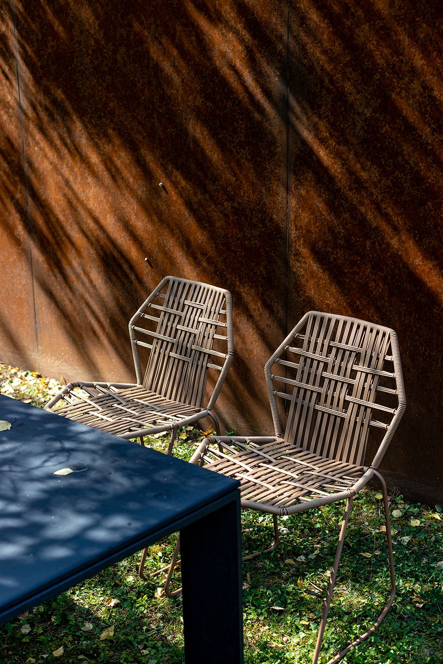 Zwei Tropicalia TR0 Outdoor Stühle aus Polymer von Moroso neben einem Tisch im Garten.