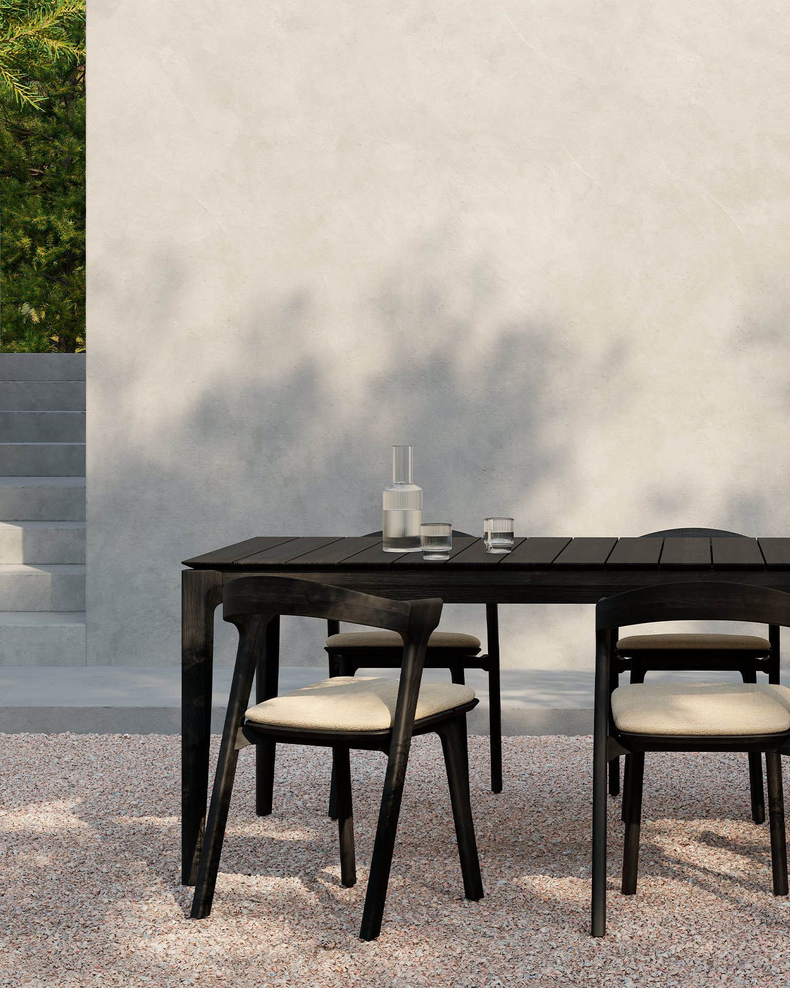 Schwarzer Ethnicraft Bok Outdoor Teak Esstisch (250 cm) mit Stühlen im Garten.