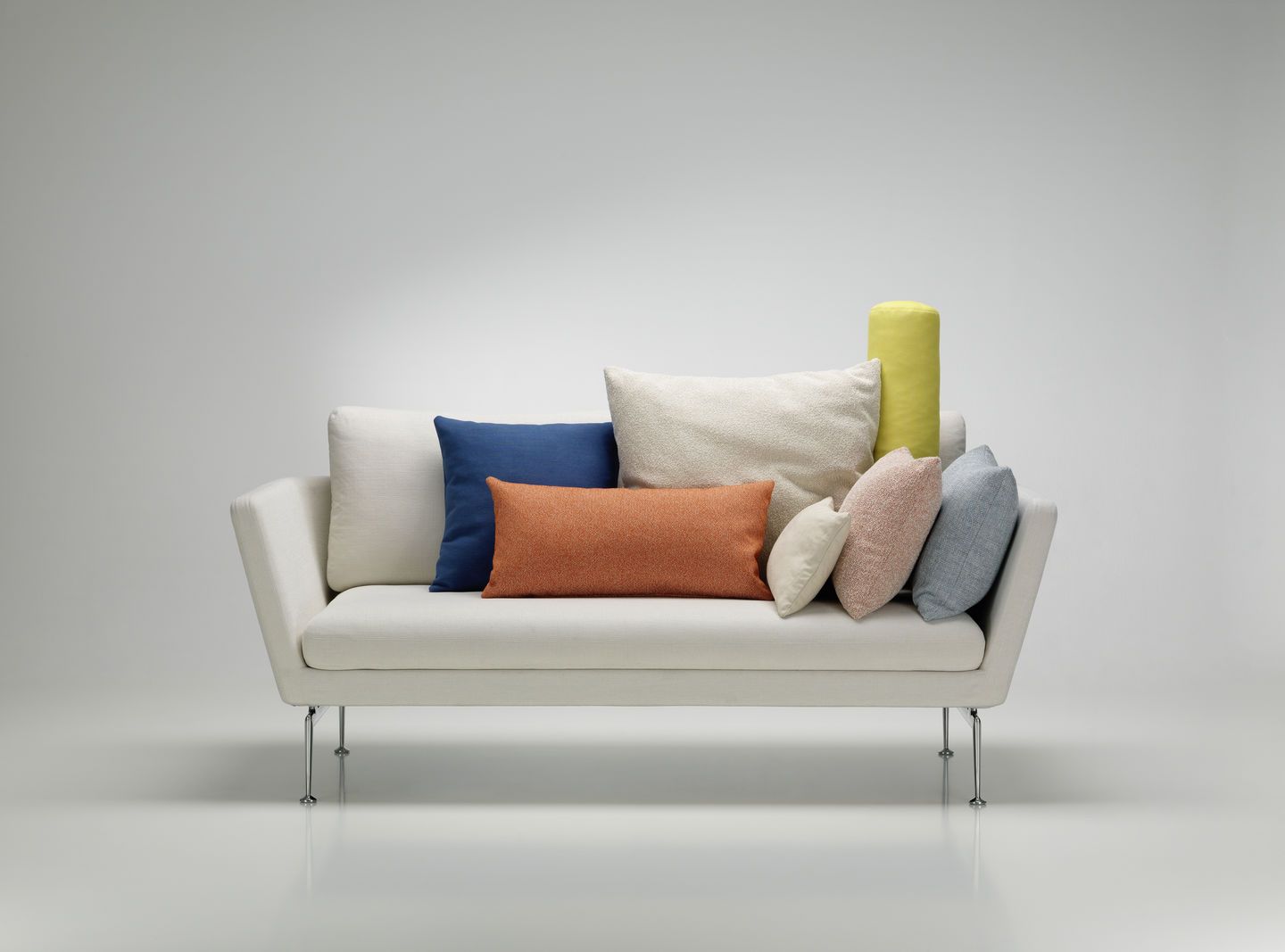 Weißes Sofa mit verschiedenen farbigen Vitra Kissen und Sofakissen in Blau, Orange, Beige und Gelb.