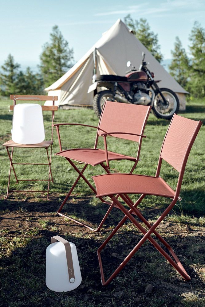 Zwei rote Fermob Plein Air Stühle im Freien, Camping-Szene mit Zelt und Motorrad.