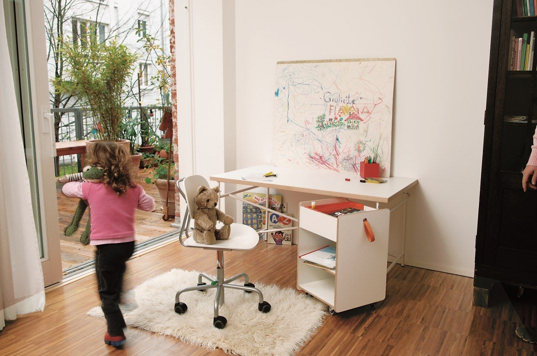 Eiermann Kinderschreibtisch von Richard Lampert im Kinderzimmer mit Stuhl, Rollcontainer und spielendem Kind.