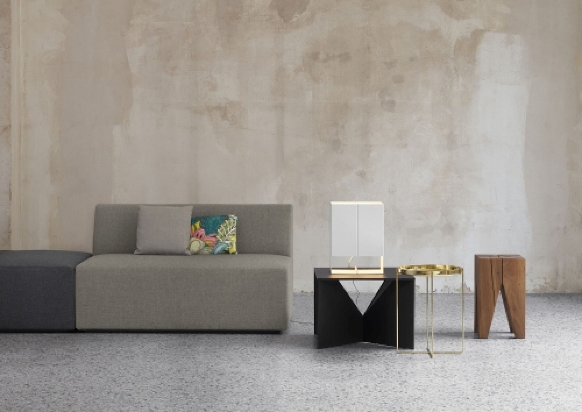 SF06 Kerman Modulsofa von e15, graues Stoffsofa mit Kissen und Beistelltischen vor beiger Wand.