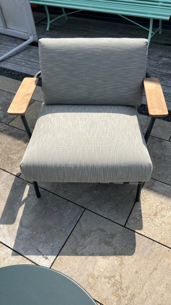 Muuto Settle Lounge Sessel für den Außenbereich, grauer Stoffbezug und Armlehnen aus Holz.
