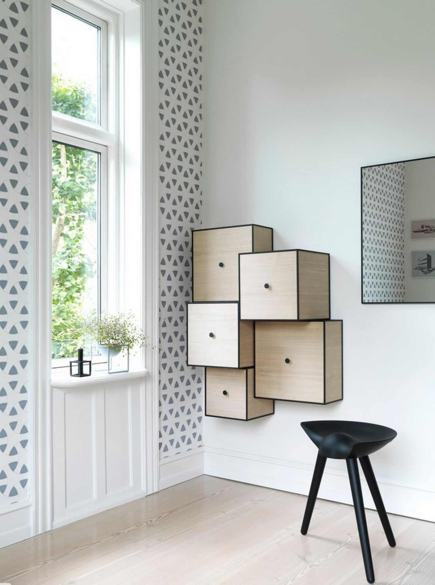 Schwarzer ML42 Hocker Audo aus Holz vor einer Wand mit Holzschränken und Spiegel.