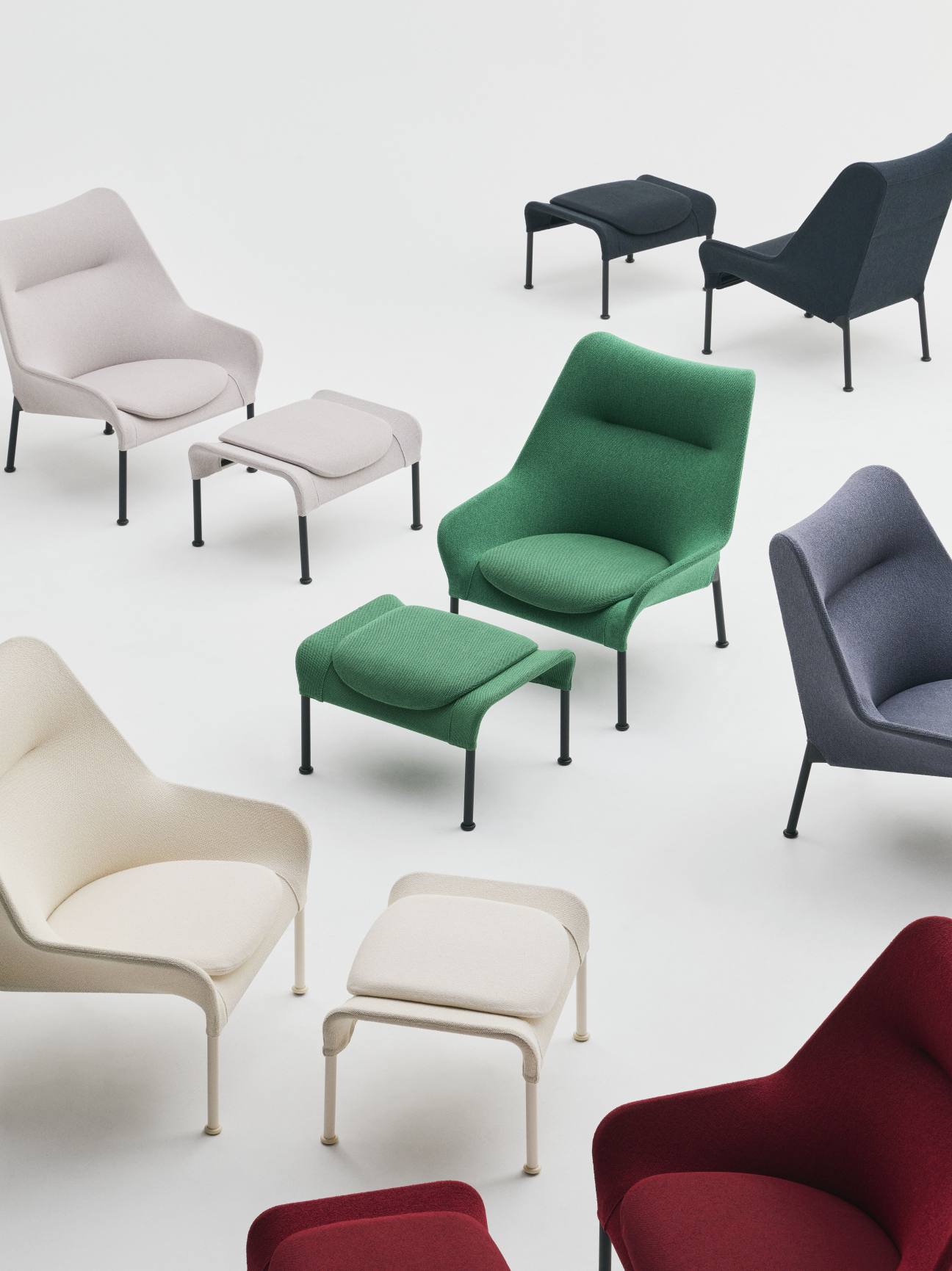 Mehrere farbige Hay 02 Ottoman Hocker und Sessel auf weißem Hintergrund, modernes Wohnzimmer Design.