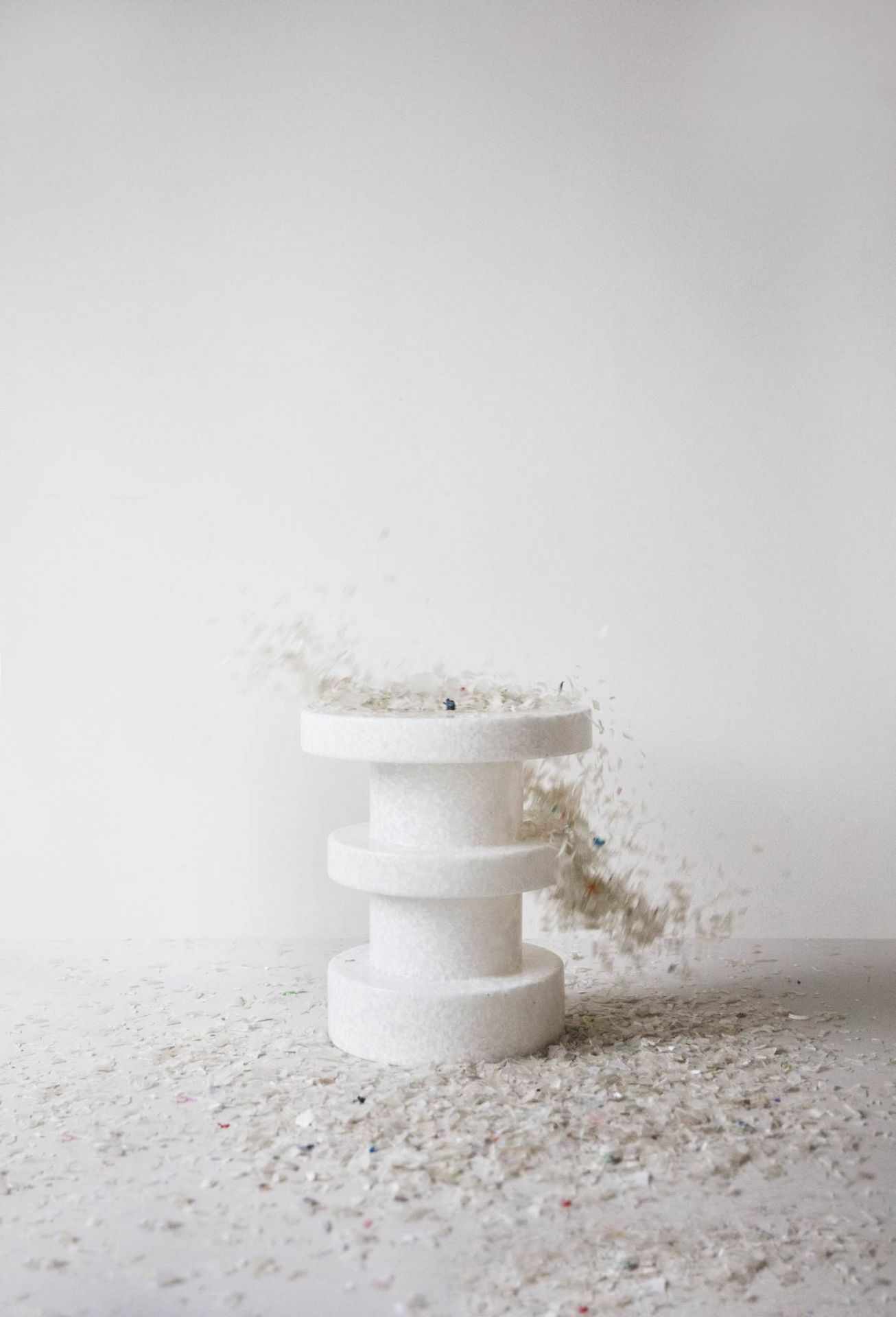 Weißer Bit Stool Stack Hocker von Normann Copenhagen mit herumfliegenden und liegenden Plastikpartikeln.