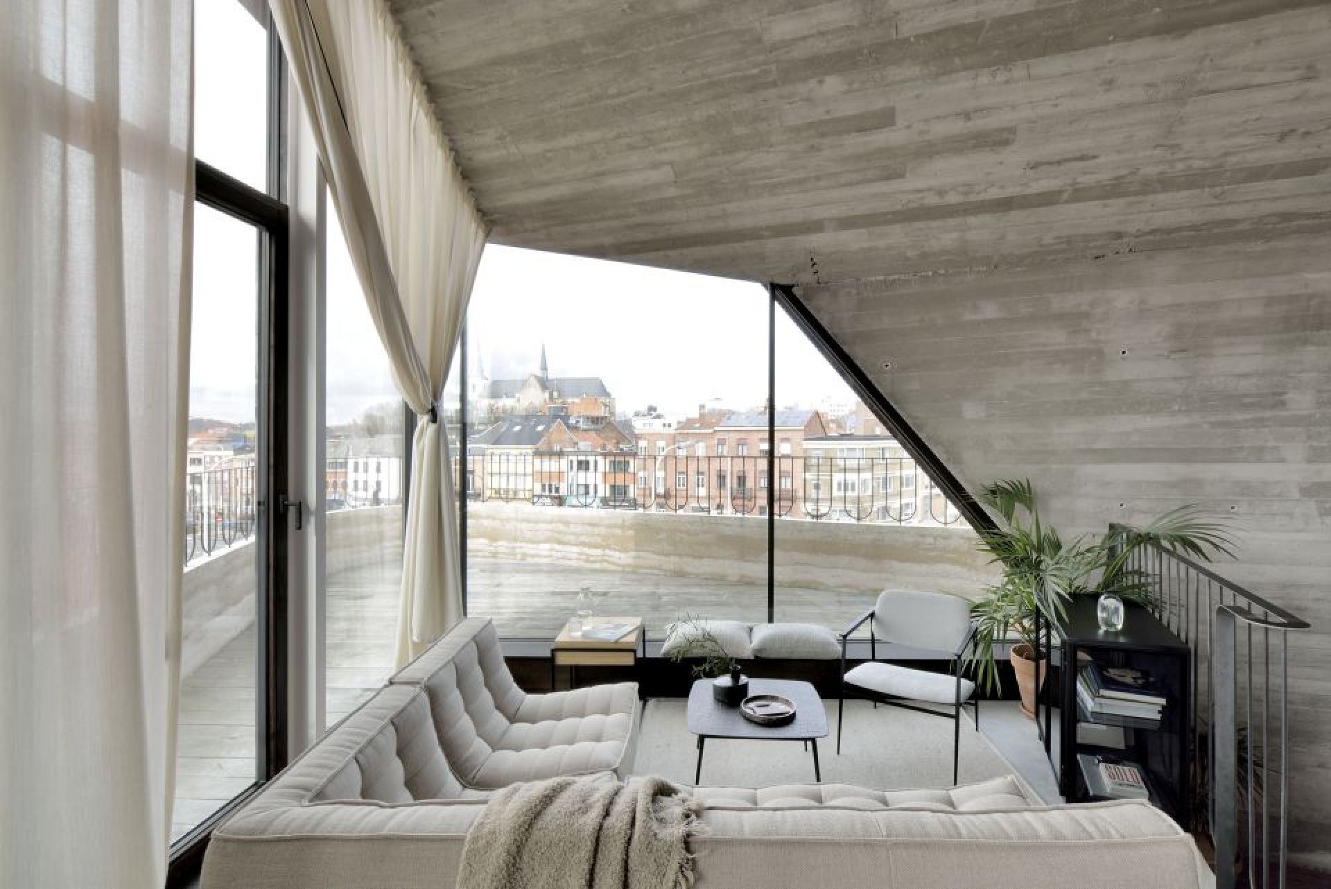 Helles Wohnzimmer mit Ethnicraft Sofa, N701 Ecksofa, Couchtisch und großem Fenster mit Stadtblick.
