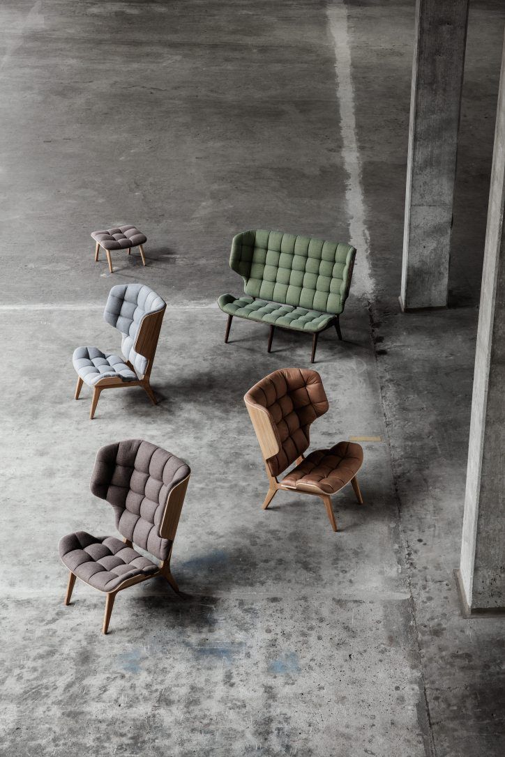 Mehrere NORR11 Mammoth Chair Sessel in verschiedenen Farben und ein passender Hocker auf Betonboden.
