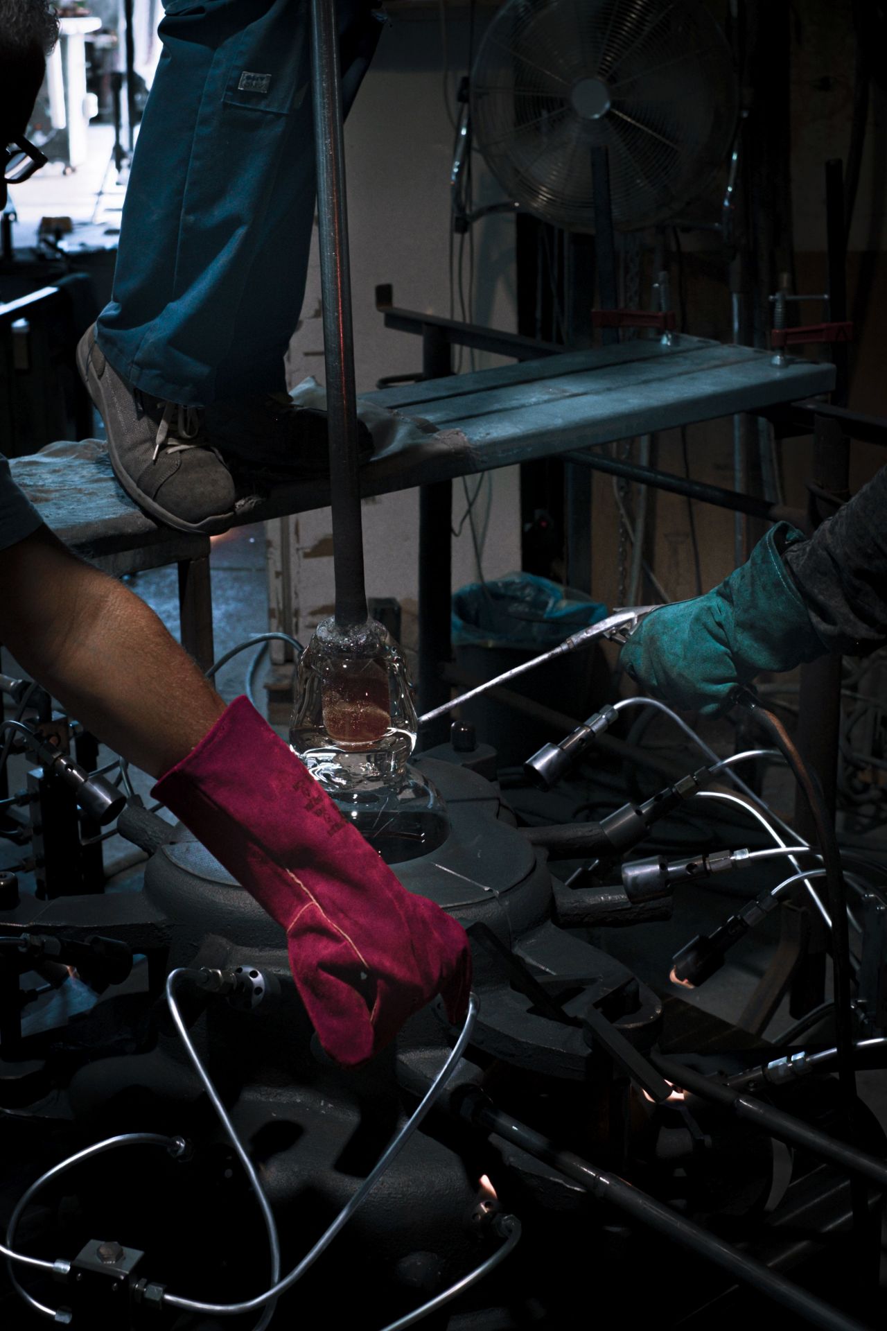 Glasbläser formen geschmolzenes Glas mit Werkzeugen und Hitze, um einen Beistelltisch herzustellen.