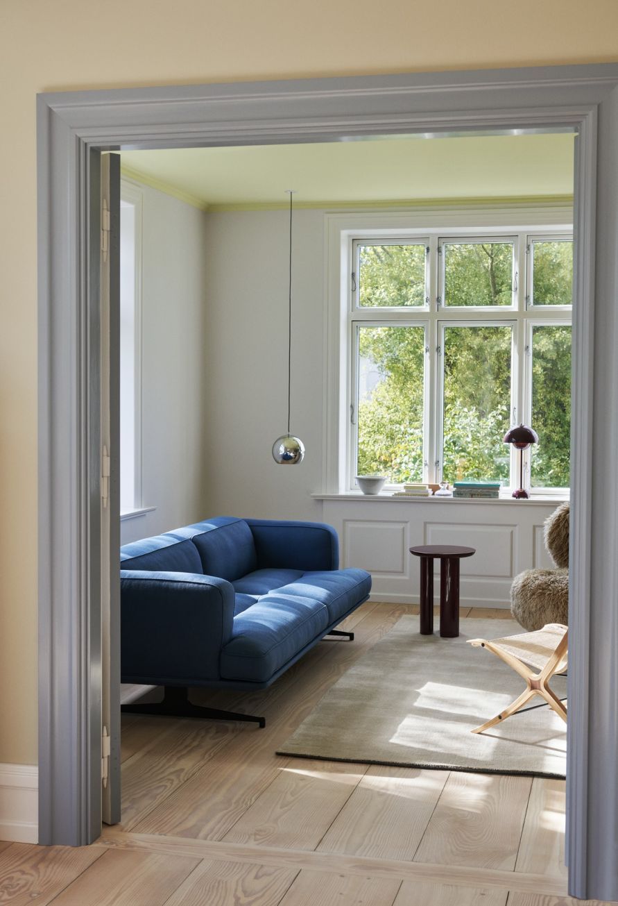 Wohnzimmer mit blauem Sofa, Holzboden und Flowerpot VP3 Pendelleuchte von AndTradition über dem Couchtisch.