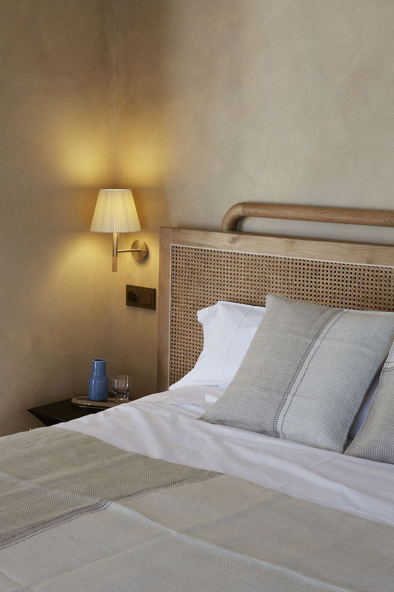 Nahaufnahme eines Hotelbettes mit BC2 Wandleuchte von Santa & Cole für stimmungsvolle Beleuchtung.