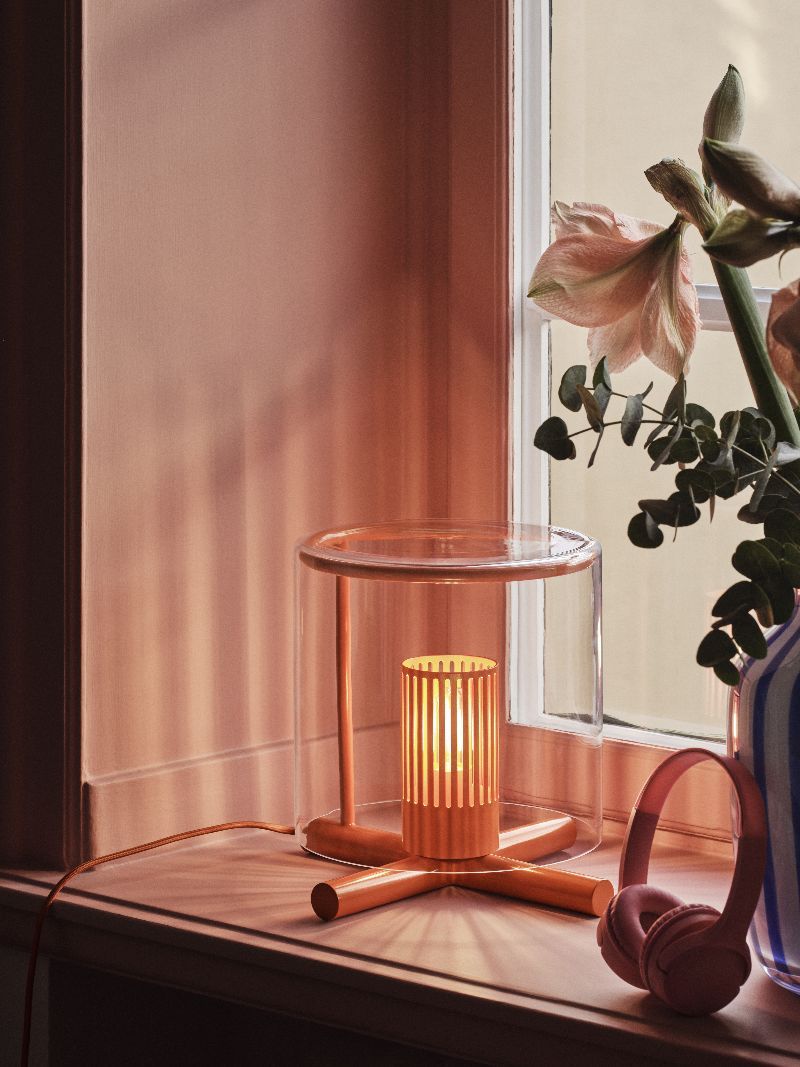 Fireplace Lamp Tischleuchte von Design House Stockholm auf Fensterbank mit Kopfhörern und Blumenvase.