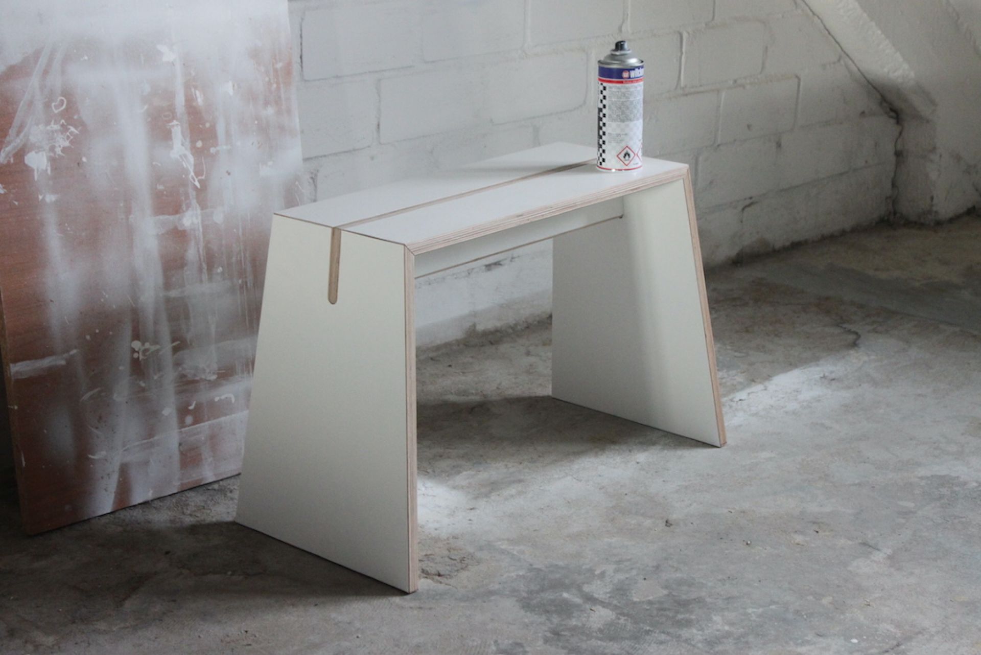 Tojo Stubenhocker: Moderner, weißer Hocker aus Holz mit minimalistischem Design und einer Sprühdose darauf.