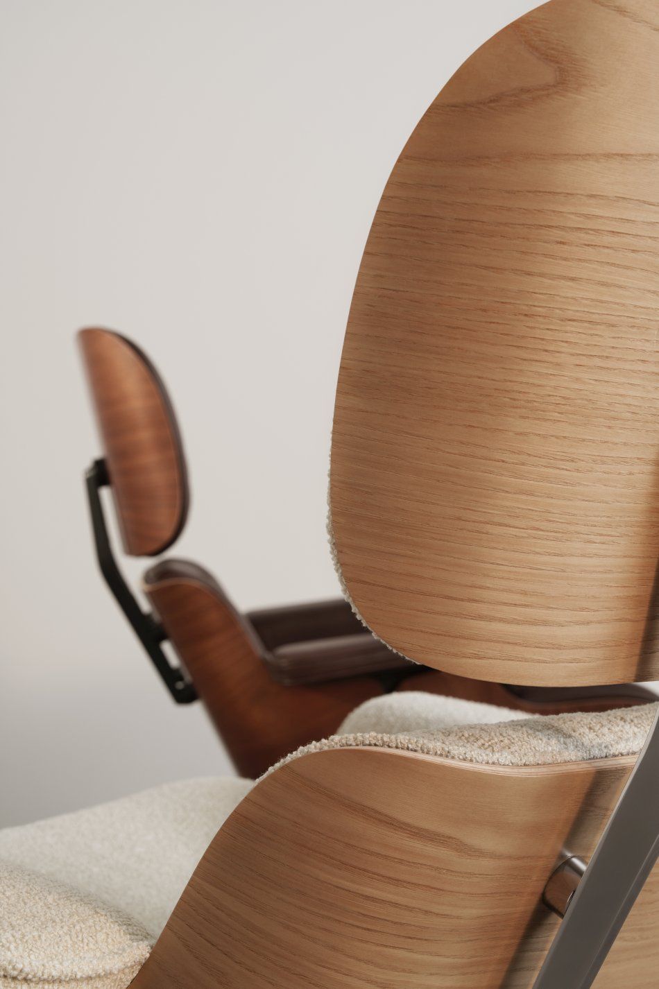 Detailaufnahme: Eames Lounge Chair Sessel mit hellem Bezug und Holzschale, Designklassiker für Wohnzimmer und Büro.