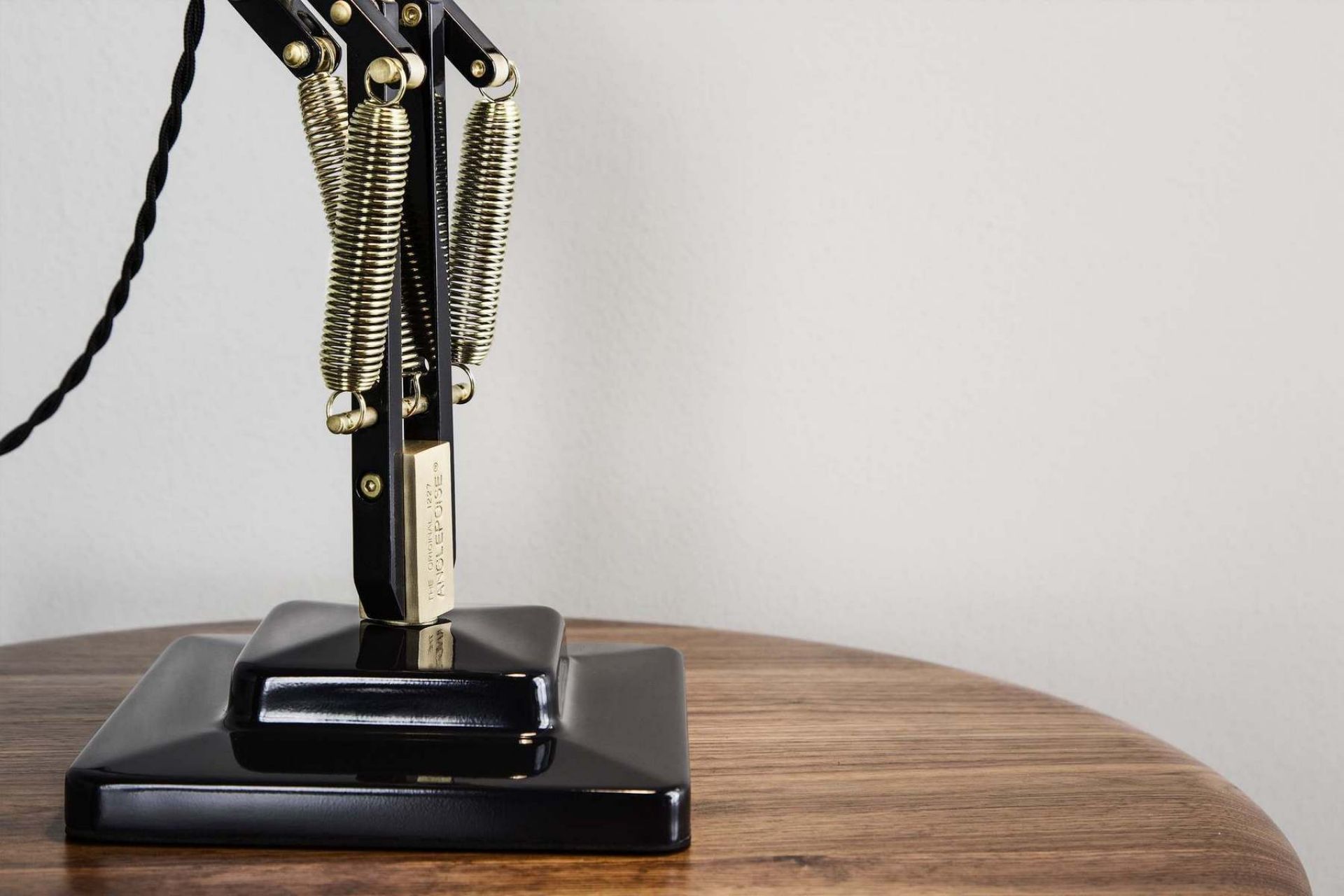 Detailaufnahme der Original 1227 Anglepoise Tischleuchte in Messing und Schwarz auf einem Holztisch.