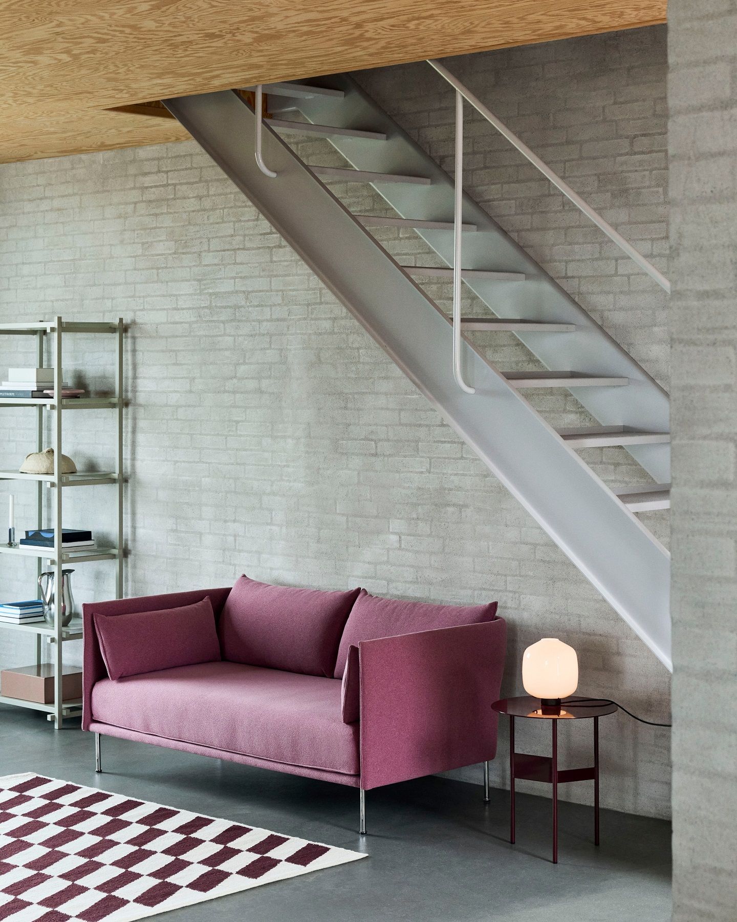 Helle Aspekt Buoy Tischleuchte von Hay auf kleinem Tisch neben lila Sofa im Wohnzimmer.