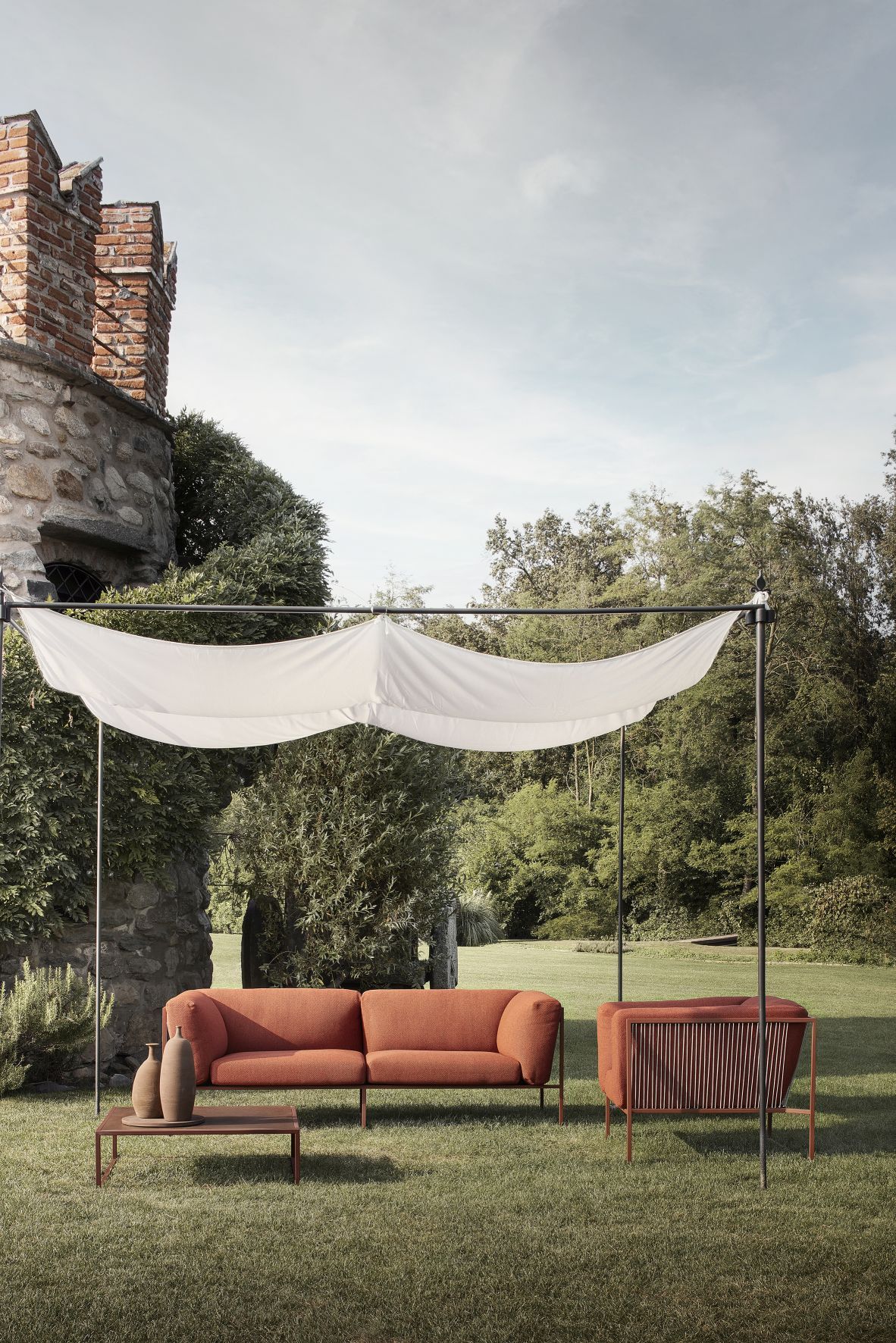 Arpa Outdoor Sessel von MDF Italia mit Sofa, Sessel und Tisch auf Rasenfläche.