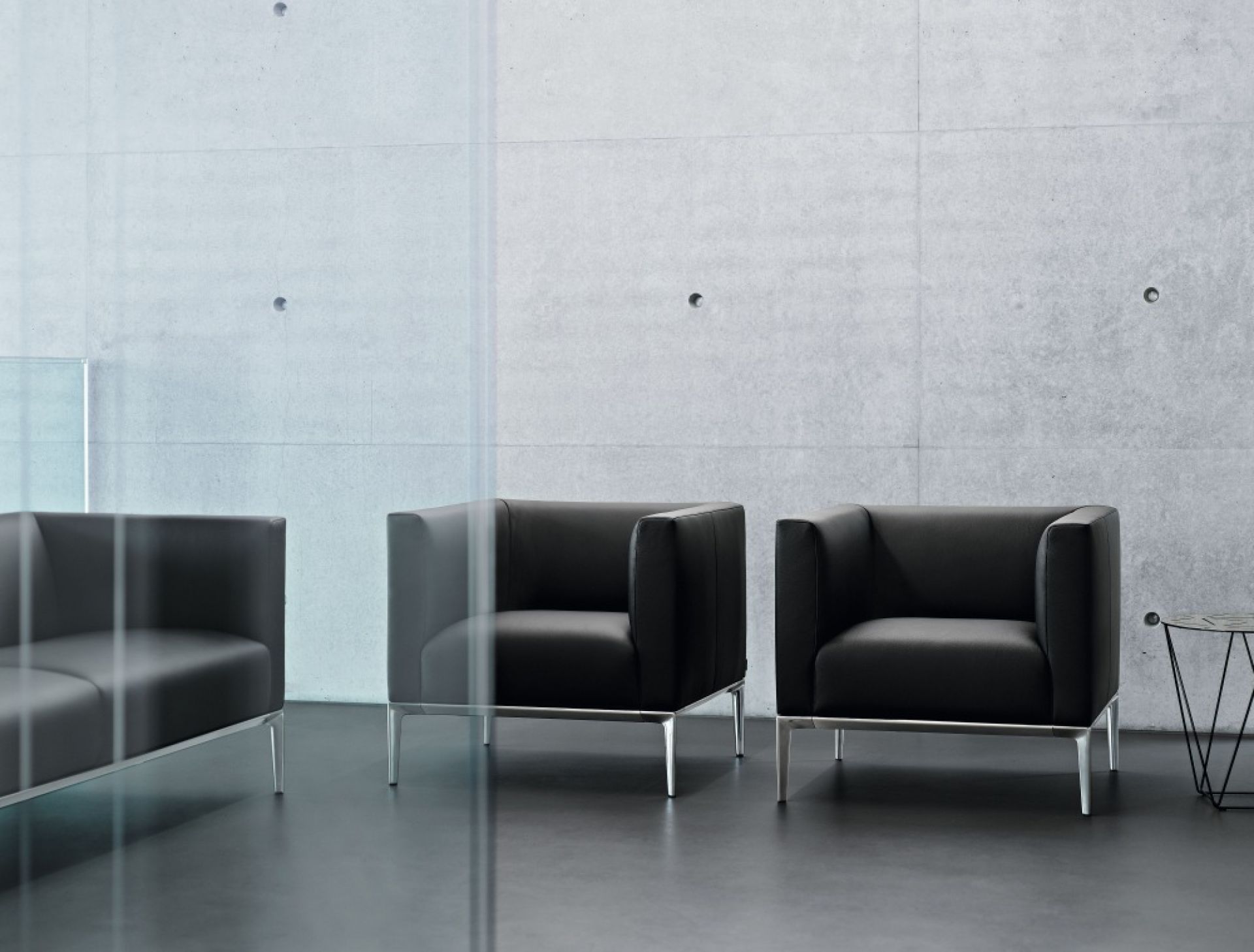 Schwarzer Jaan Sessel von Walter Knoll mit Metallbeinen vor einer Betonwand.