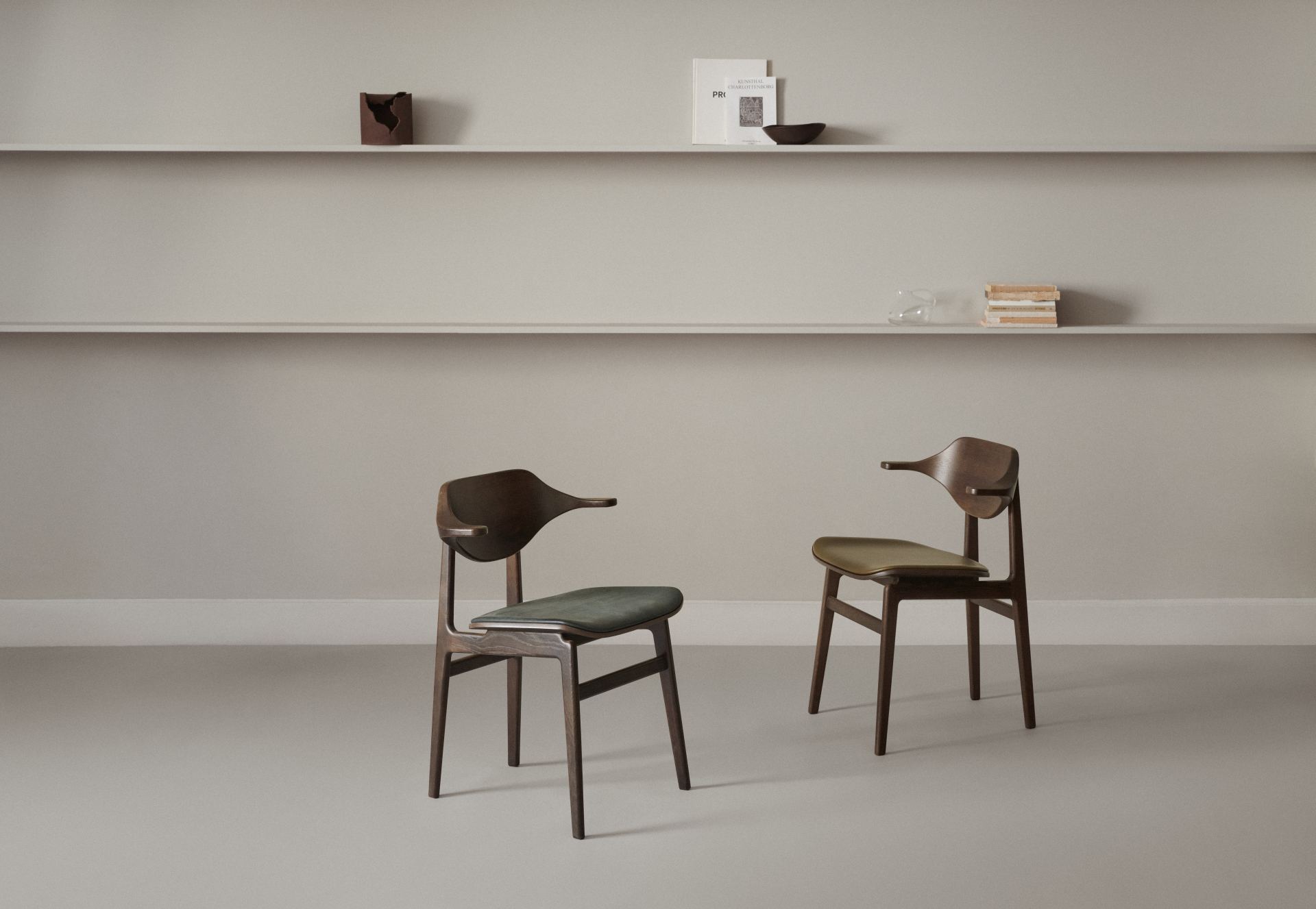 Zwei Bufala Dining Chairs von NORR11 aus dunklem Holz mit Armlehnen und Lederbezug.