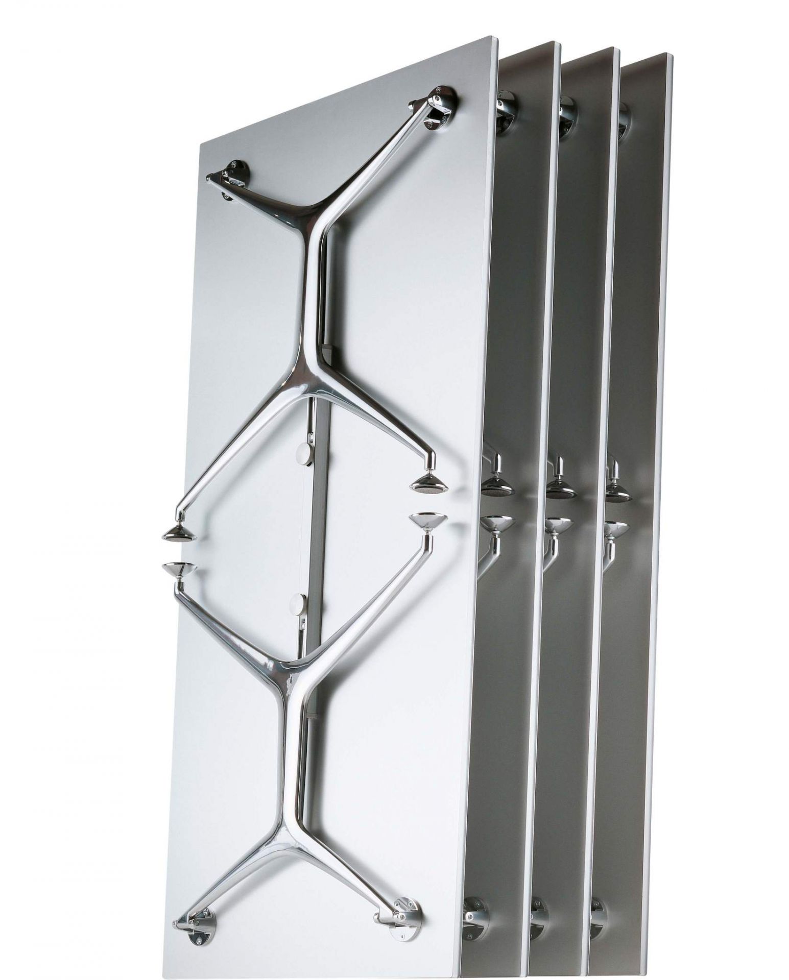 Frametable Tisch Alias: Vier zusammengeklappte, platzsparende Tische mit verchromten Tischbeinen an einer Wand.