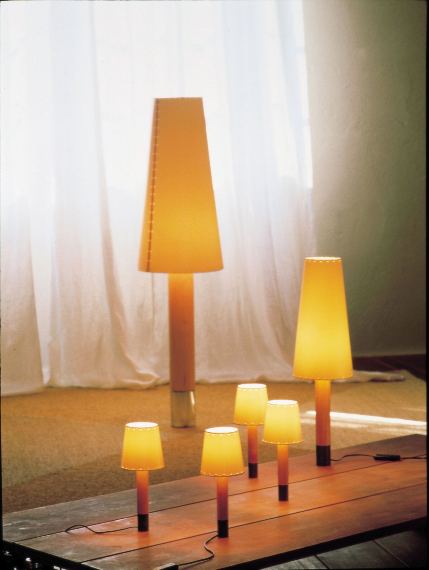 Basica Tischleuchten von Santa & Cole: Verschiedene Größen der Design-Lampe mit gelbem Schirm.
